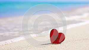 Flag of Morocco in the shape of a heart on a sandy beach.