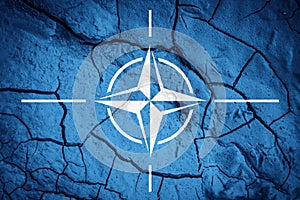 Flag of NATO. North Atlantic Treaty Organization flag. Flag on the background of dry cracked earth.