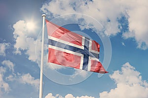 Flag of Norway, National symbol waving against cloudy, blue sky, sunny day