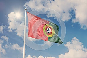 Flag of Portugal, National symbol waving against cloudy, blue sky, sunny day