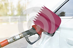 Flag of Qatar on the car`s fuel filler flap with gas pump nozzle in the tank