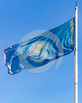 Flag of the Republic of Kazakhstan waving in the wind against the blue sky