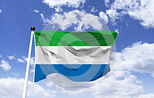 Flag of the Republic of Sierra Leone. Trembling under a blue sky.