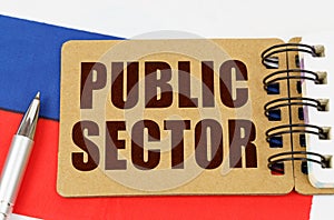 On the flag of Russia lies a pen and a notepad with the inscription - PUBLIC SECTOR