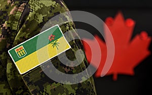 Flag of Saskatchewan on the military uniform and red Maple leaf on the background. Flag of Canadian province of Saskatchewan.