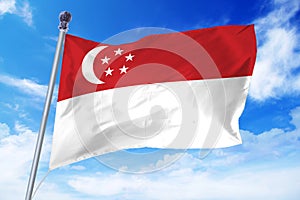 Flag of Singapore developing against a clear blue sky