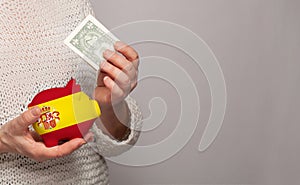 Flag of Spain on money bank in Spanish woman hands. Dotations, pension fund, poverty, wealth, retirement concept