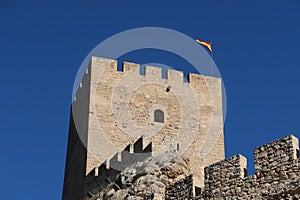 Flag of Spain on the tower of the Almohad castle of Sax on top of a rock. Sax, Alicante, Spain