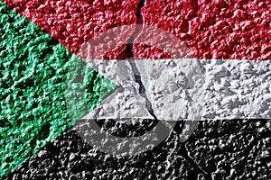 Flag of Sudan on the background of a plastered wall with a crack. Military insurgency and civil war in Sudan