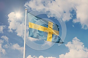 Flag of Sweden, National symbol waving against cloudy, blue sky, sunny day