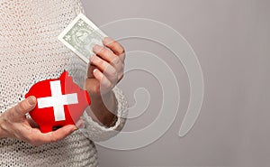 Flag of Switzerland on money bank in Swiss woman hands. Dotations, pension fund, poverty, wealth, retirement concept