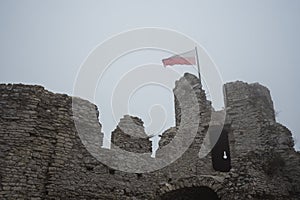 Flag on top of medieval castle ruin in heavy fog