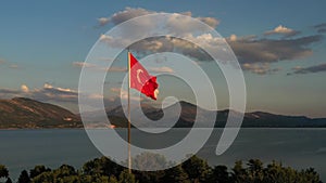 The flag of Turkey is fluttering in the wind among the beautiful landscape of turkish nature with Egirdir lake