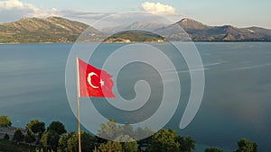 The flag of Turkey is fluttering in the wind among the beautiful landscape of turkish nature with Egirdir lake