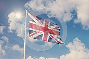Flag of UK, National symbol waving against cloudy, blue sky, sunny day