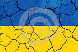 Flag of Ukraine on the texture of cracked earth. Russian-Ukrainian military conflict