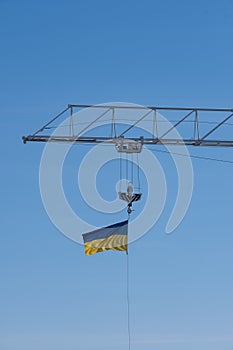 The flag of Ukraine waving in the wind on the top of a construction crane boom