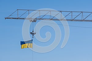 The flag of Ukraine waving in the wind on the top of a construction crane boom