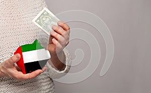 Flag of United Arab Emirates on money bank in UAE woman hands. Dotations, pension fund, poverty, wealth, retirement concept