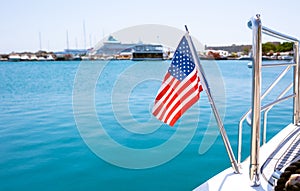 The flag of the United States flutters in the wind on a stainless steel flagpole at the stern of a motor yacht. Marina in the port