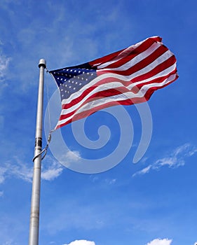 Flag of USA blowing on a pole against blue sky