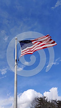 Flag of USA blowing on a pole against blue sky