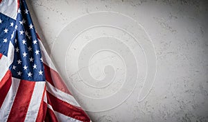 Flag of USA hangs on textured gray wall. Vibrant colors of stars and stripes stand out, symbolizing patriotism and national pride