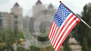Flag of the USA set against blue sky and city. American flag-waving. Copy space