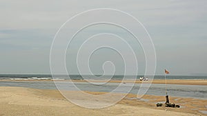 Flag in the wind against the background of people with motorcycles rolling along the light sandy sea coast