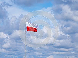 On flagpole the red and white flag of Poland is waving