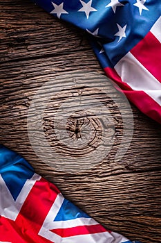 Flags of american and united kingdom on rustic oak board. UK and USA flags together diagonally