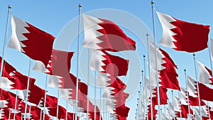 Flags of Bahrain on flagpole against blue sky.