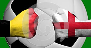 Flags of Belgium and England painted on two clenched fists facing each other with closeup 3d soccer ball in the background/Soccer