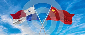 flags of China and Panama waving in the wind on flagpoles against sky with clouds on sunny day. Symbolizing relationship, dialog