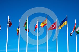 Flags of Different Countries Hang On Flagpoles Against Blue Sky. Flag of Spain, Ukraine, Mexico, Germany, Sweden, Turkey and