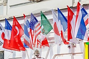 Flags of different countries posted in a row on the building wall in sunny day