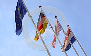 Flags from England, United Kingdom, Germany and Nederlands waving from flagpoles together with the EU, European Union, flag agains