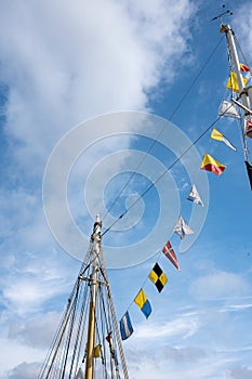 Flags of European countries hang on the mast of the yacht, against the blue sky. Bottom view.