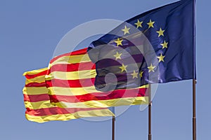 Flags of European Union and Catalonia waving together on a blue