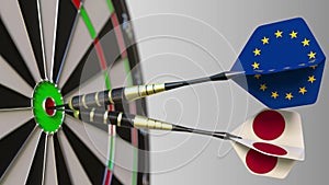 Flags of the European Union and Japan on darts hitting bullseye of the target. International cooperation or competition