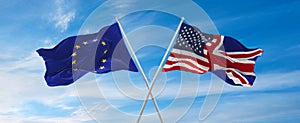 flags of European Union, United Kingdom, United States of America waving in wind on flagpoles against sky with clouds on sunny day