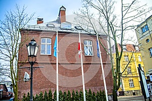 Flags on flagpoles near the wall of the building of the house