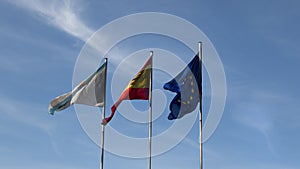 Flags of Galicia, Spain and the European Union together in front of the blue sky