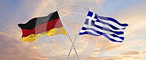 flags of Germany and Greece waving in the wind on flagpoles against sky with clouds on sunny day. Symbolizing relationship, dialog