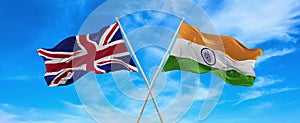 flags of great Britain and India waving in the wind on flagpoles against sky with clouds on sunny day. Symbolizing relationship,