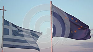 Flags of Greece and EU waving in wind against blue sky background, debt crisis