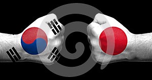 Flags of Japan and South Korea painted on two clenched fists facing each other on black background/.Japanâ€“South Korea relations