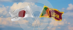 flags of Japan and Sri Lanka waving in the wind on flagpoles against sky with clouds on sunny day. Symbolizing relationship,
