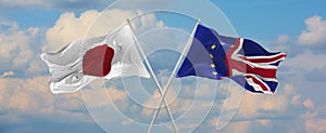 flags of Japan and Union Jack And Flag Of European Union waving in the wind on flagpoles against sky with clouds on sunny day.