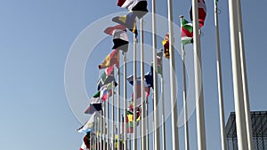 Flags of many Nations against a blue sky - national flags of various countries waving in the wind